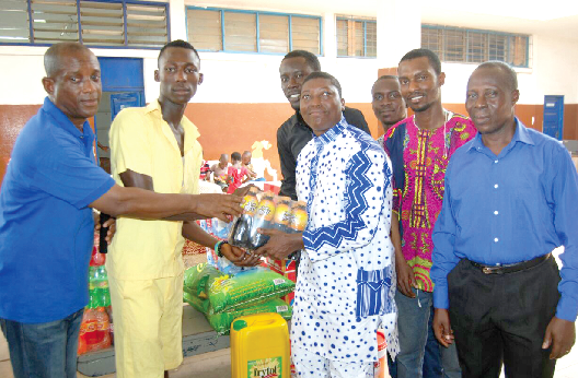 Mr Kwesi Reynolds Jackson, a musician and founder of the Reynolds Foundation (right), presenting the items to Mr Tetteh and Master Okyere, the Assistant Headmaster of the school and the school prefect respectively